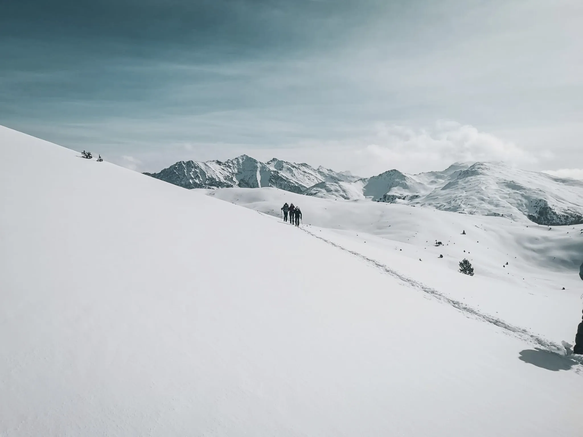A group of hikers on a vast expanse of snow with mountains in the background, inviting adventure.