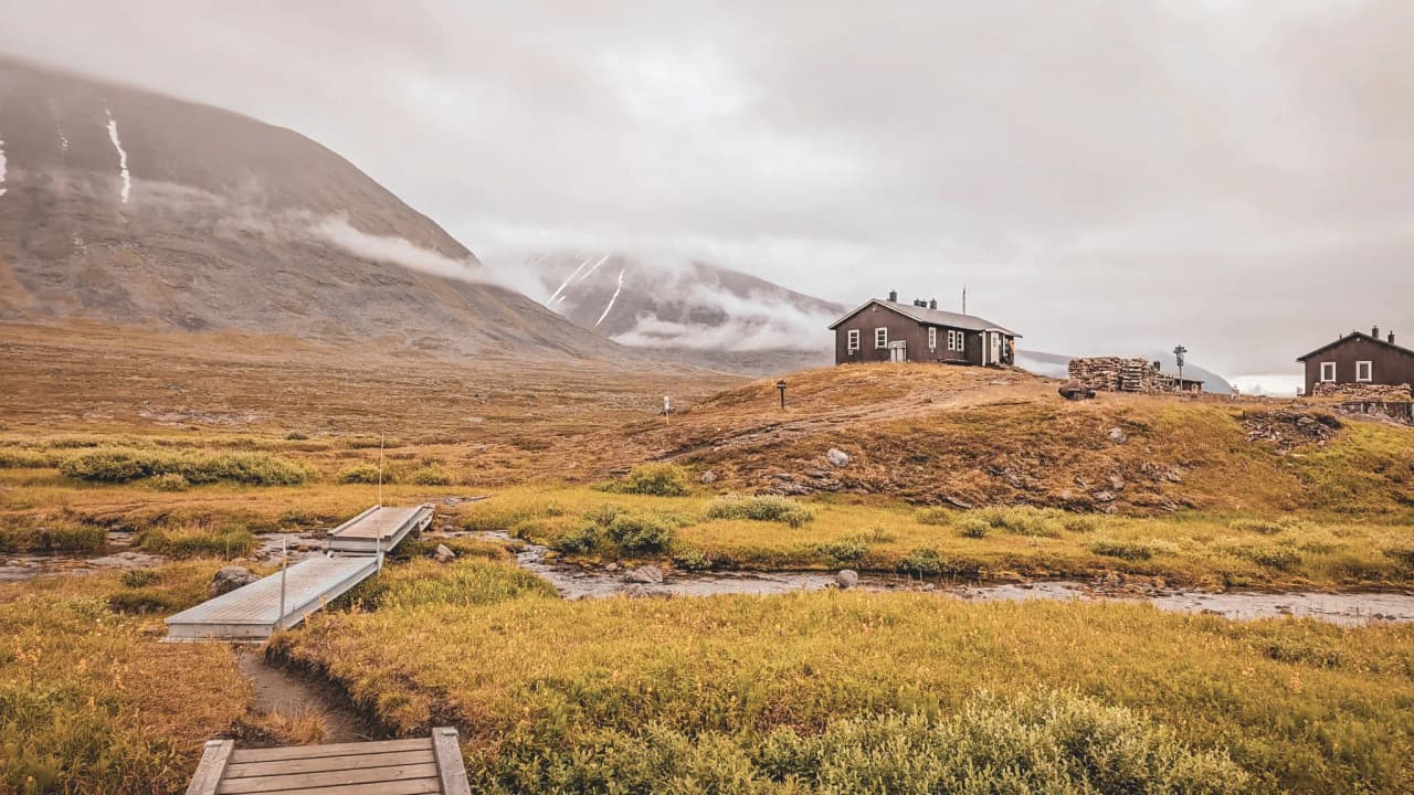 A rustic Mountain hut surrounded by rolling countryside and green valleys in Swedish Lapland.