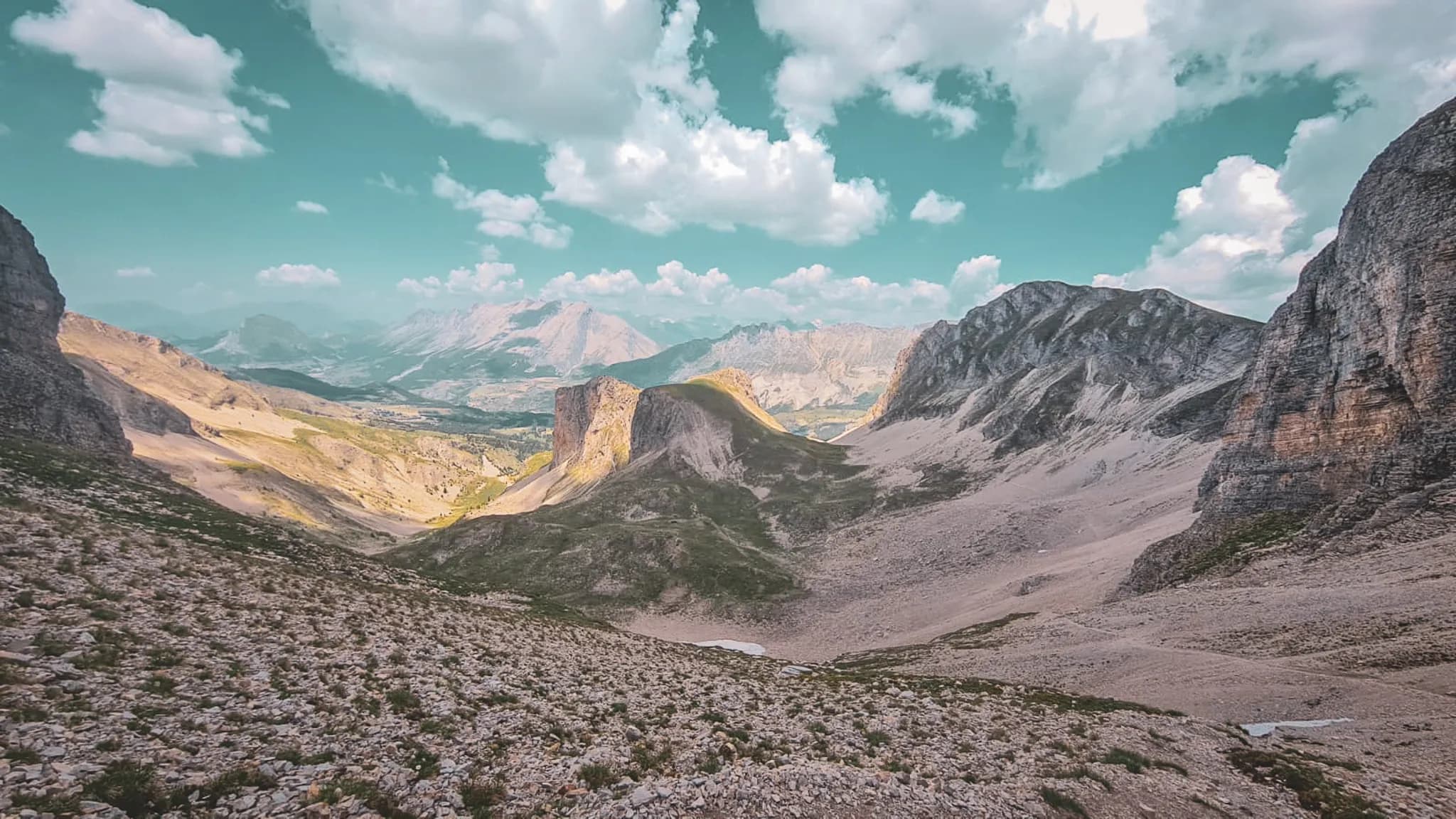 A breathtaking panorama of the Dévoluy alpine peaks, sculpted by nature, under an azure, cloudy sky.