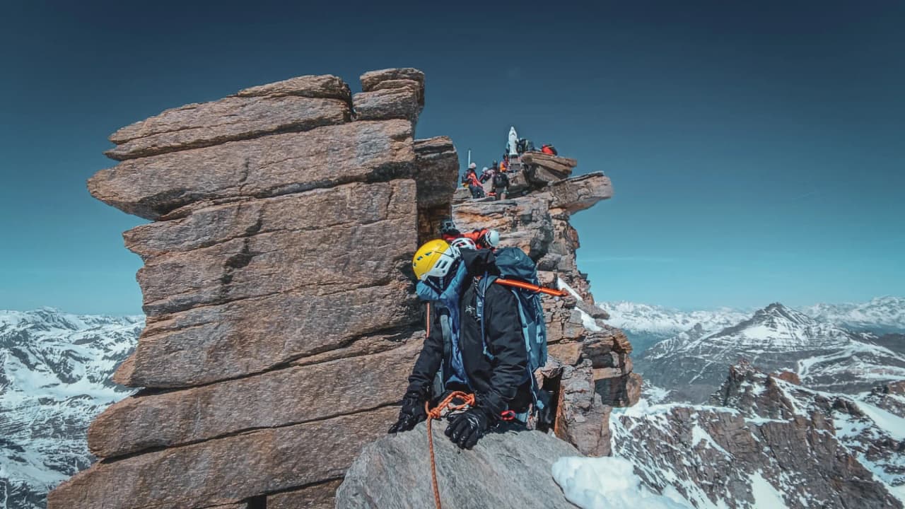 A mountaineer in full ascent of the summit of Gran Paradiso, with breathtaking mountain panoramas.