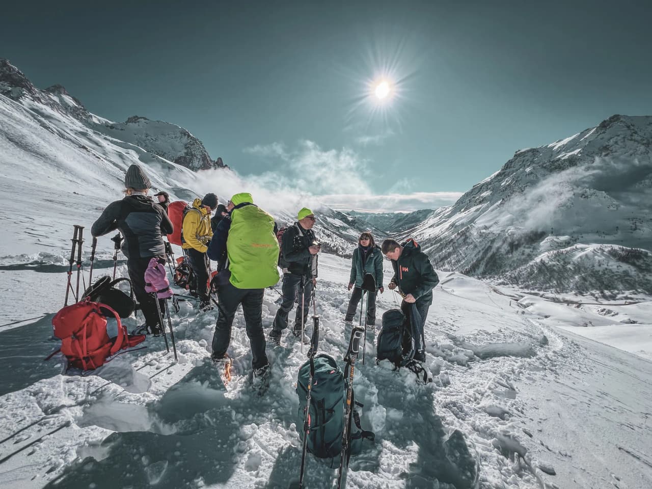 Groupe de randonneurs raquettes sous le soleil, face aux majestueux glaciers des Écrins.