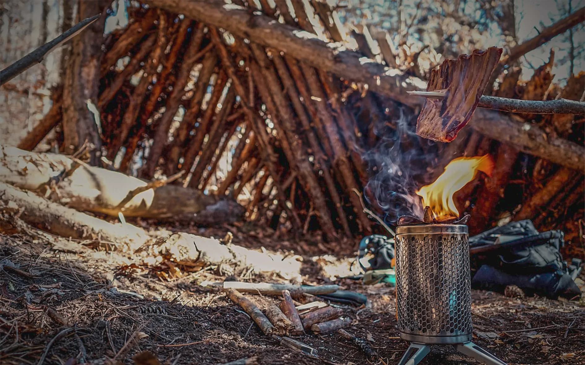 A crackling fire on a stove, with a shelter of branches in the background, a promise of adventure.