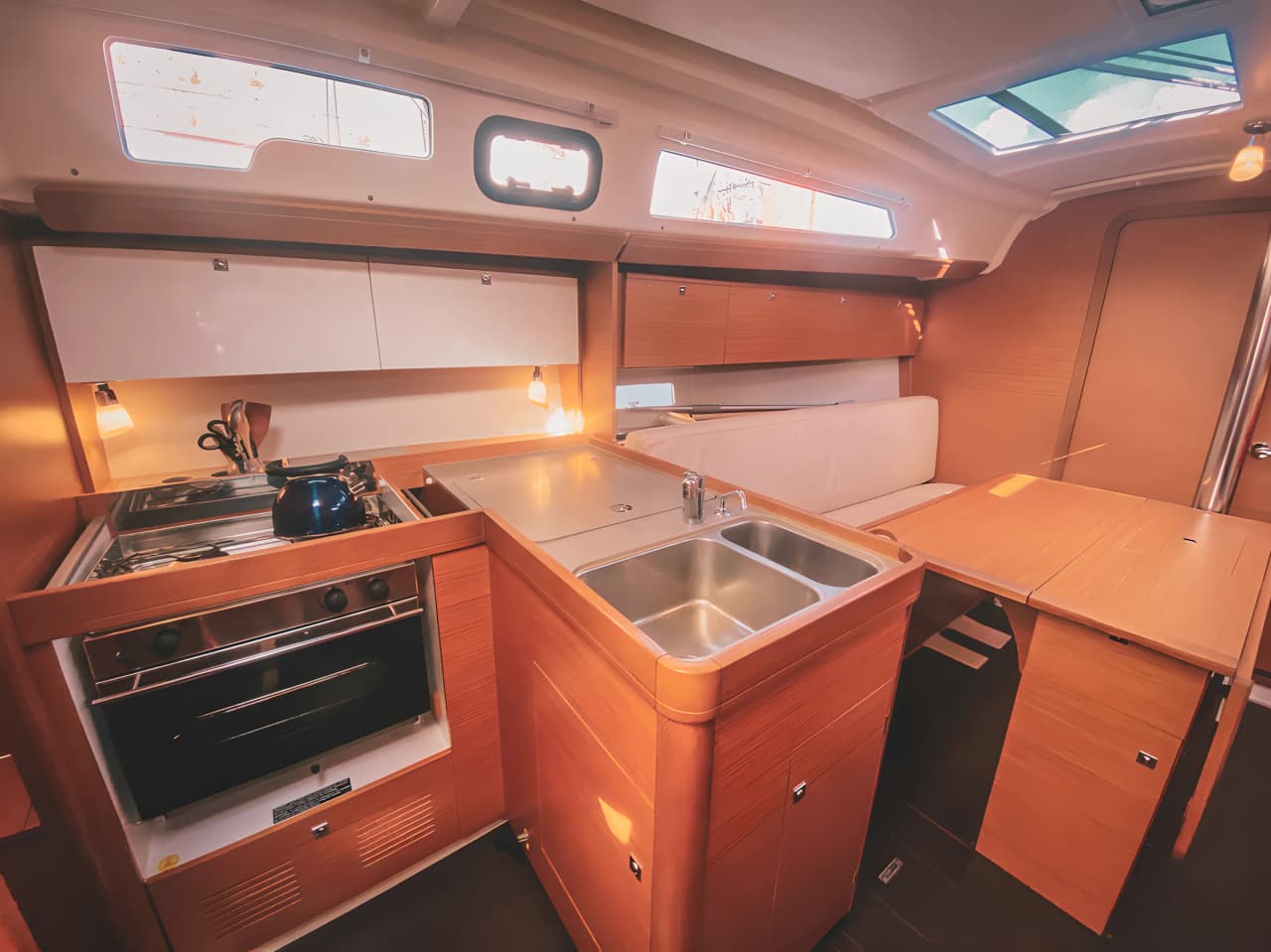 Intérieur en bois d'un voilier, lumineux et accueillant, prêt pour une aventure méditerranéenne.