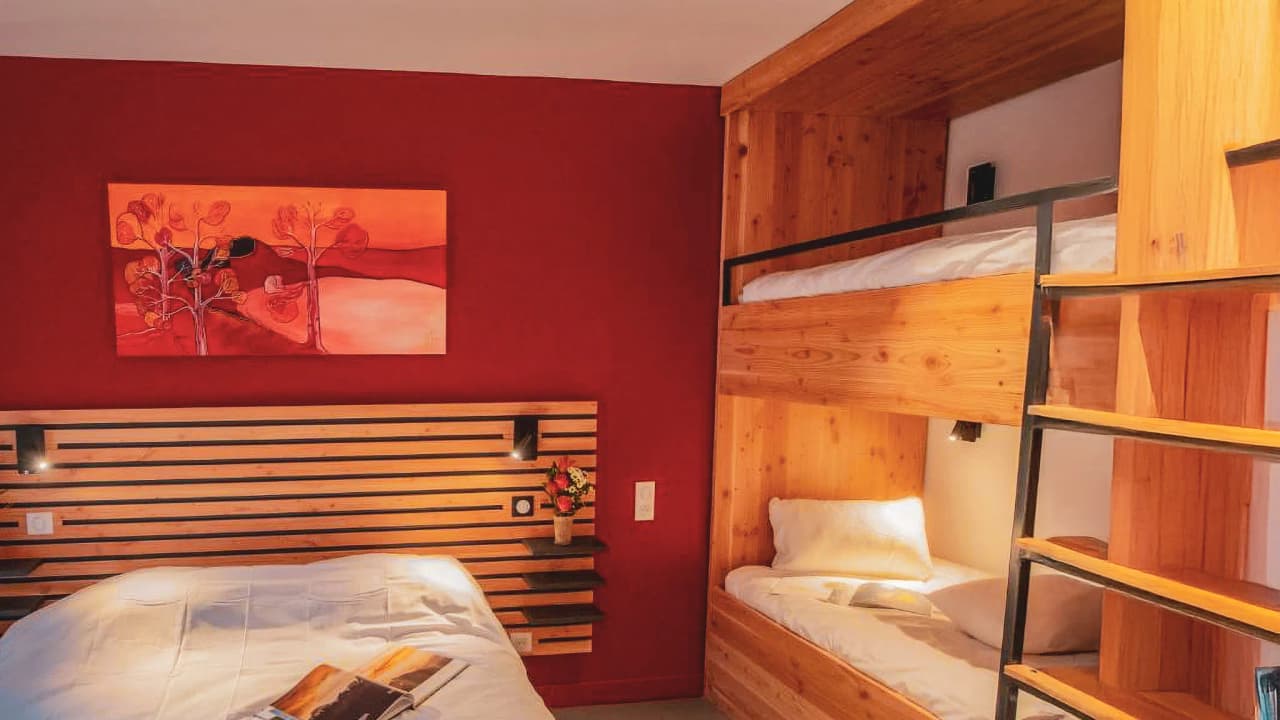 Modern bedroom in natural wood with bunk bed and colourful picture, ideal for your getaway to the Auvergne.