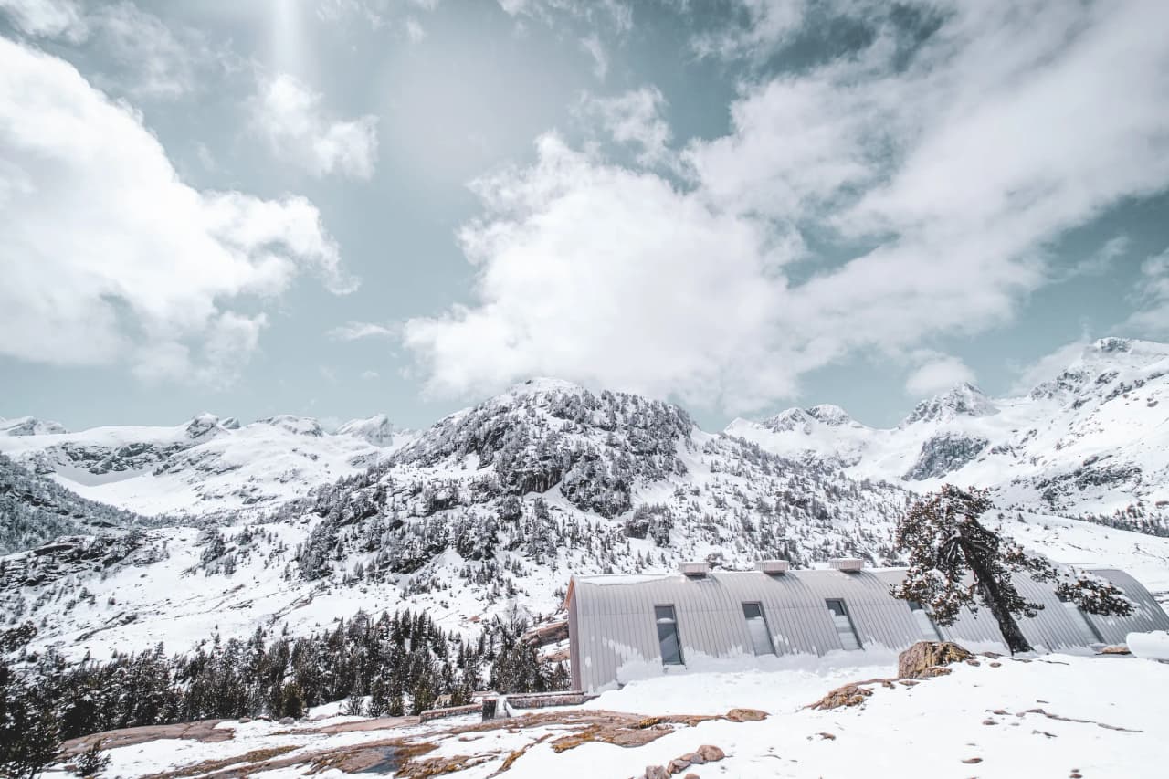 A snowy Pyrenees landscape with majestic mountains and a welcoming Mountain hut.