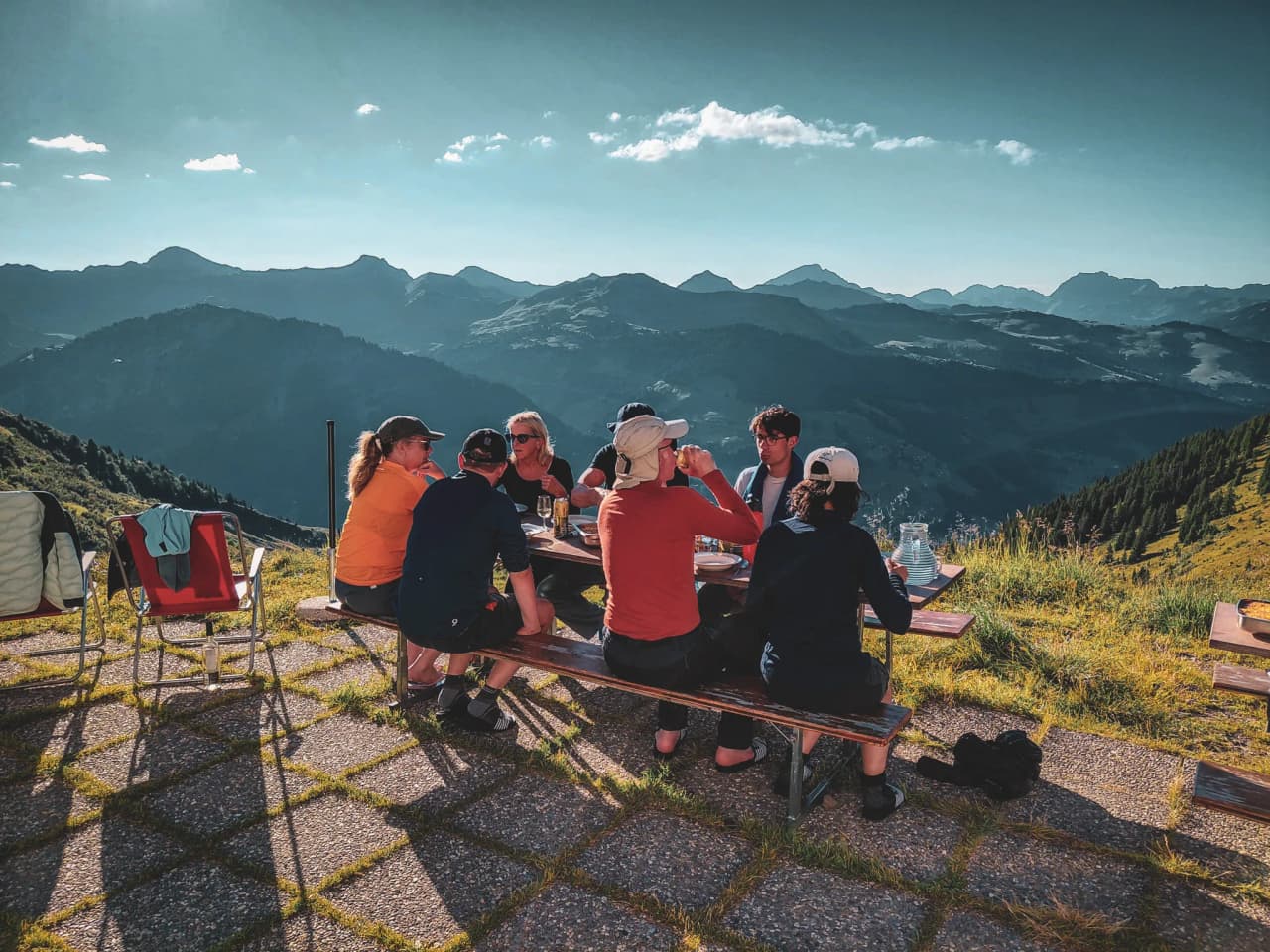 A group of hikers sharing a meal in the open air, with spectacular alpine views.
