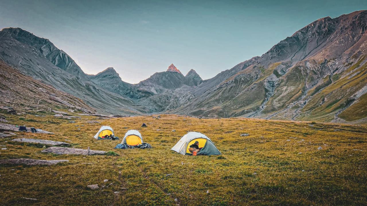 Camps sous les Aiguilles d'Arves, avec montagnes majestueuses et lumière dorée du crépuscule.