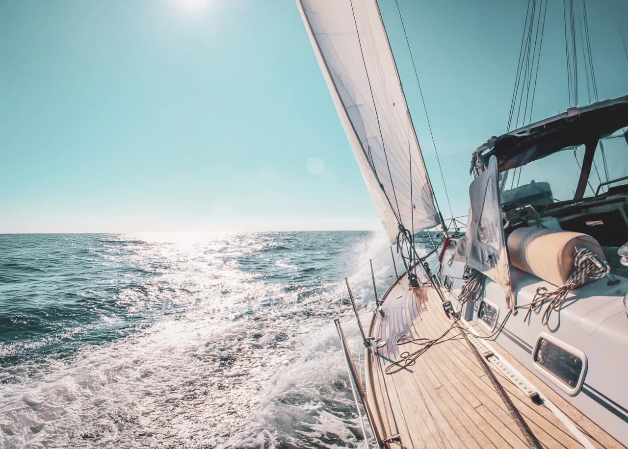 Un voilier glissant sur des eaux turquoise sous un ciel ensoleillé, invitant à l'évasion.