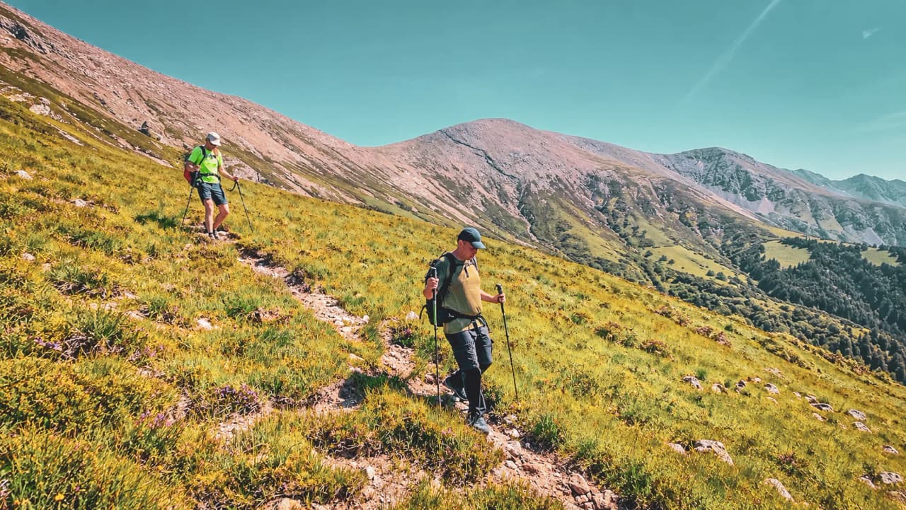 Wandelaars op de groene hellingen van de Highlands, omringd door majestueuze bergen.