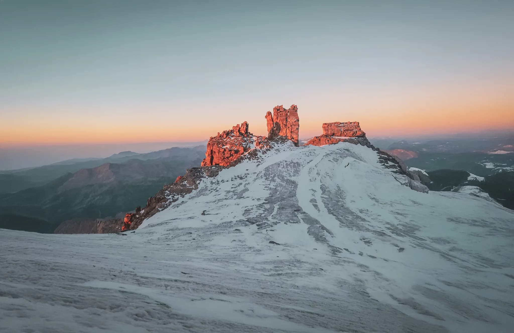 De top van Gran Paradiso met indrukwekkende rotsformaties tegen de horizon. De gouden ochtendzon verlicht de bergtoppen en vormt een prachtig contrast met de besneeuwde hellingen.