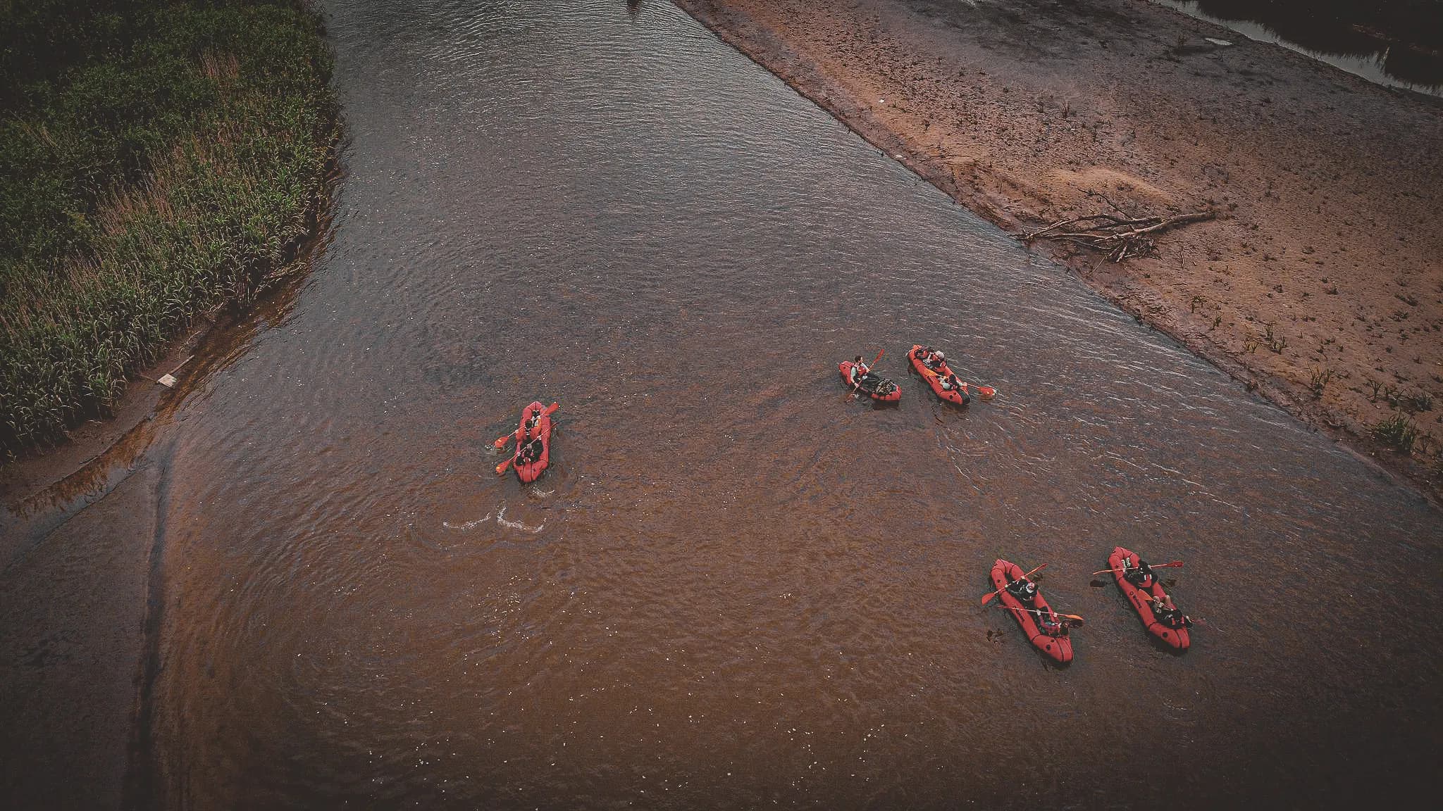Équipe en packraft naviguant sur une rivière paisible, entourée de verdure, parfait pour l'aventure.