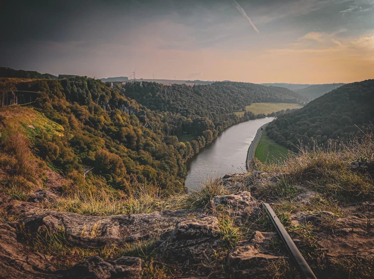 Vue panoramique sur une vallée verdoyante avec une rivière sinueuse et des falaises majestueuses.