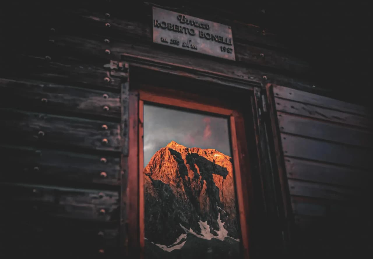 A captivating view of a summit set ablaze by the sunset, guided by a wooden window.