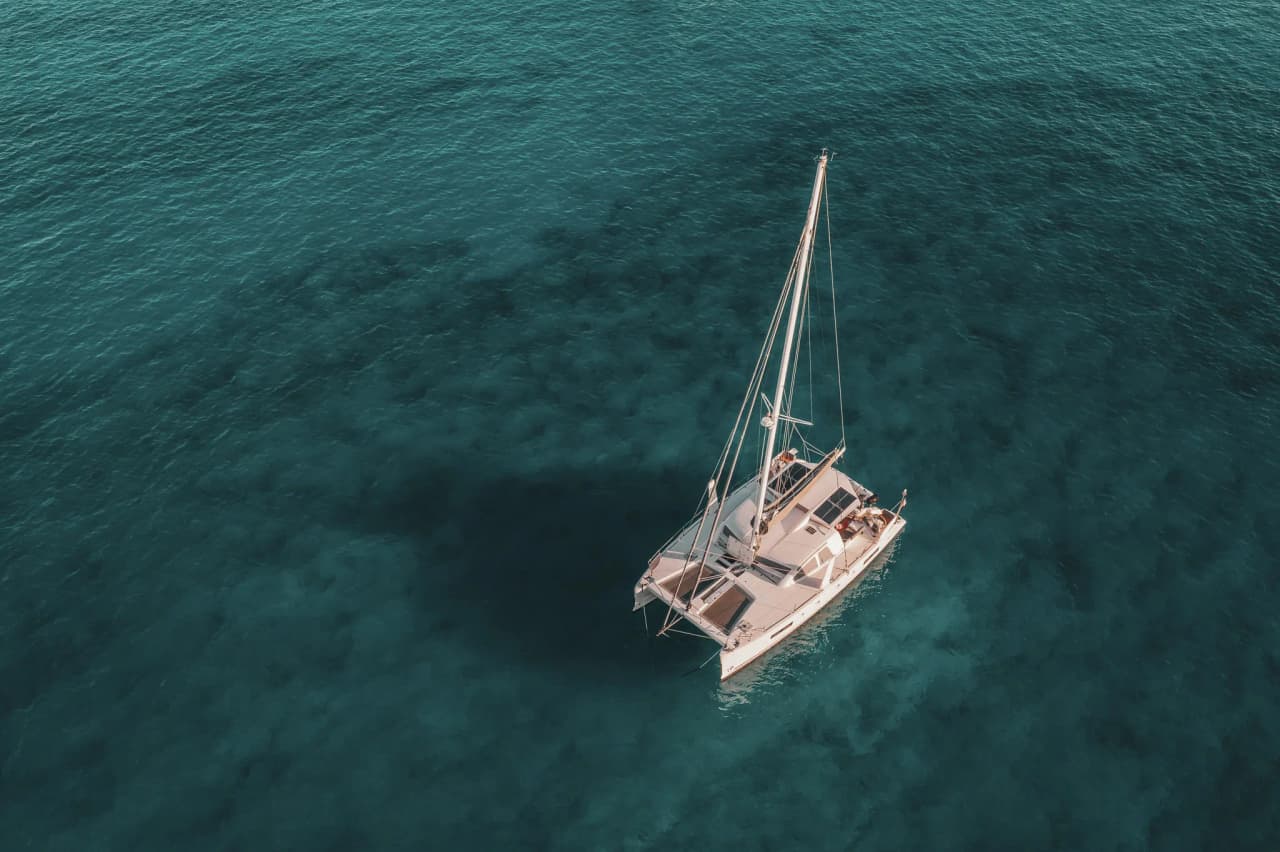 Catamaran naviguant sur des eaux turquoise, invitant à l'évasion dans les Cyclades.