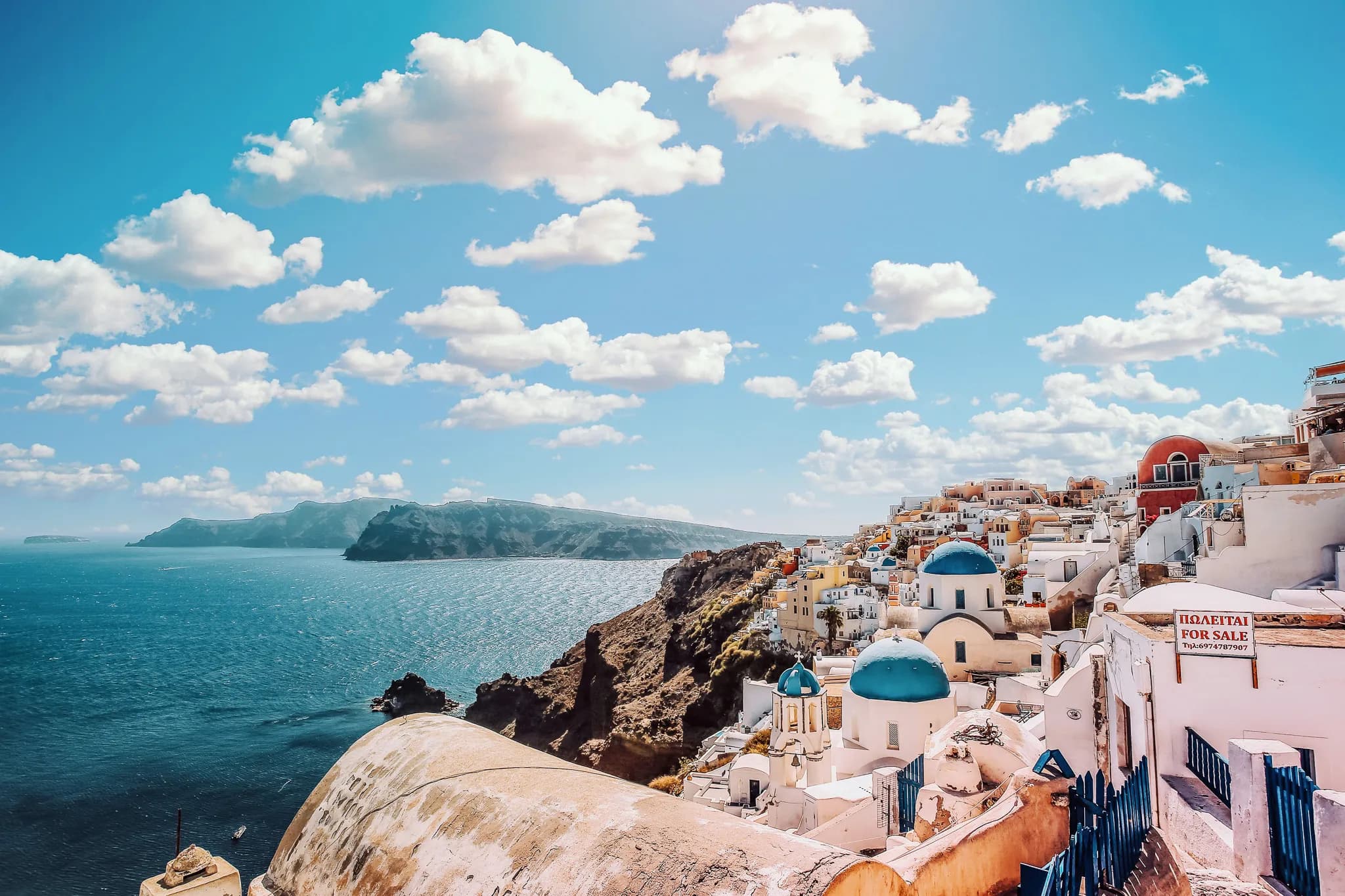 Vues enchanteresses des Cyclades, maisons blanches et bleues surplombant la mer scintillante.