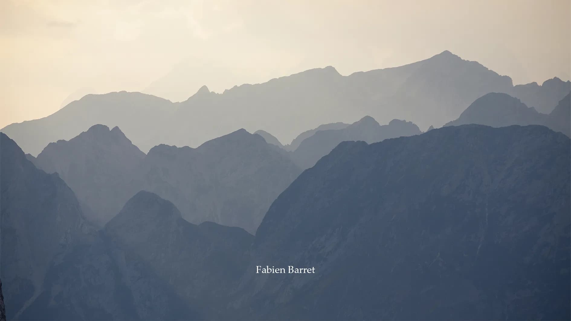 A wooden chalet sits on a green hillside, surrounded by majestic, rocky mountains. The soft light of twilight illuminates the scene, adding a peaceful ambience. Nearby, a few