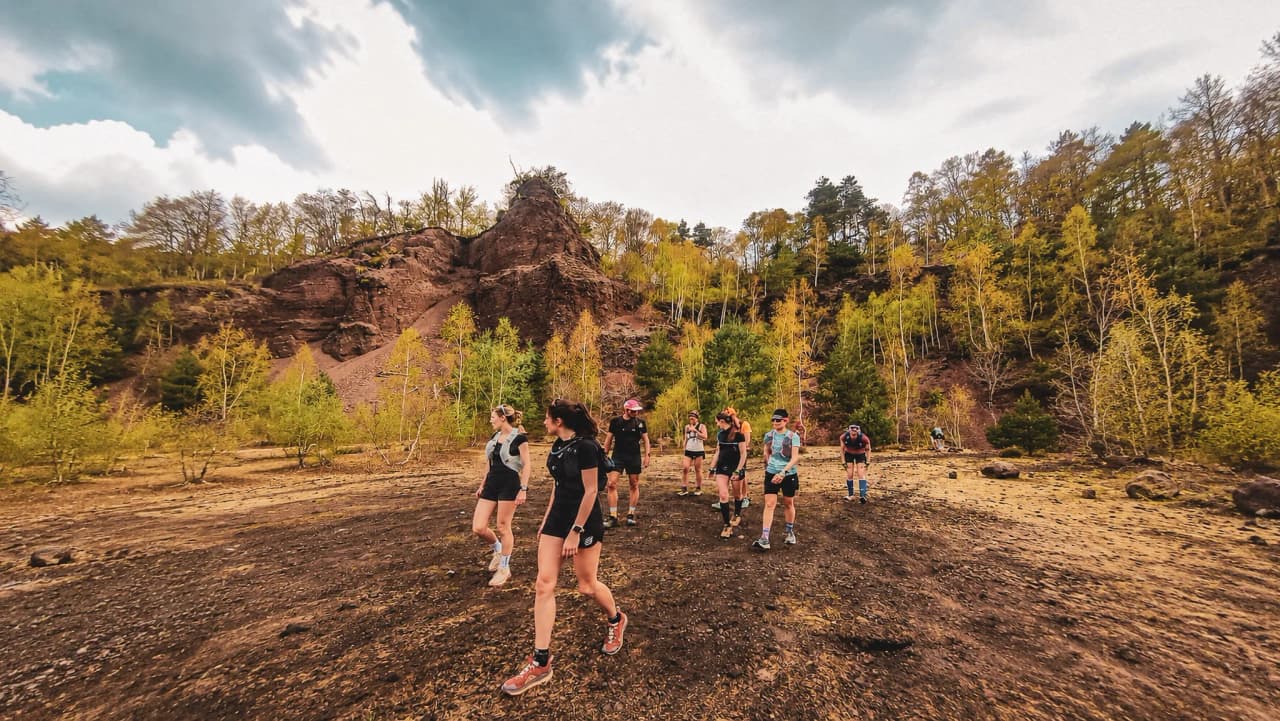 A group of athletes exploring the volcanic landscapes of the Auvergne, under cloudy skies.