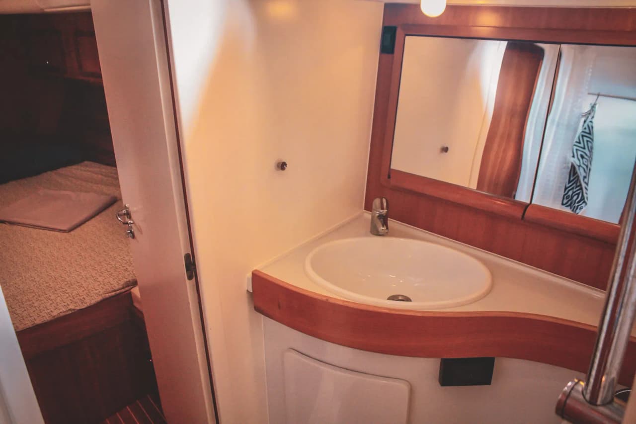 Intérieur d'un voilier, avec lavabo moderne et lit cosy à l'arrière, invitant à l'aventure maritime.