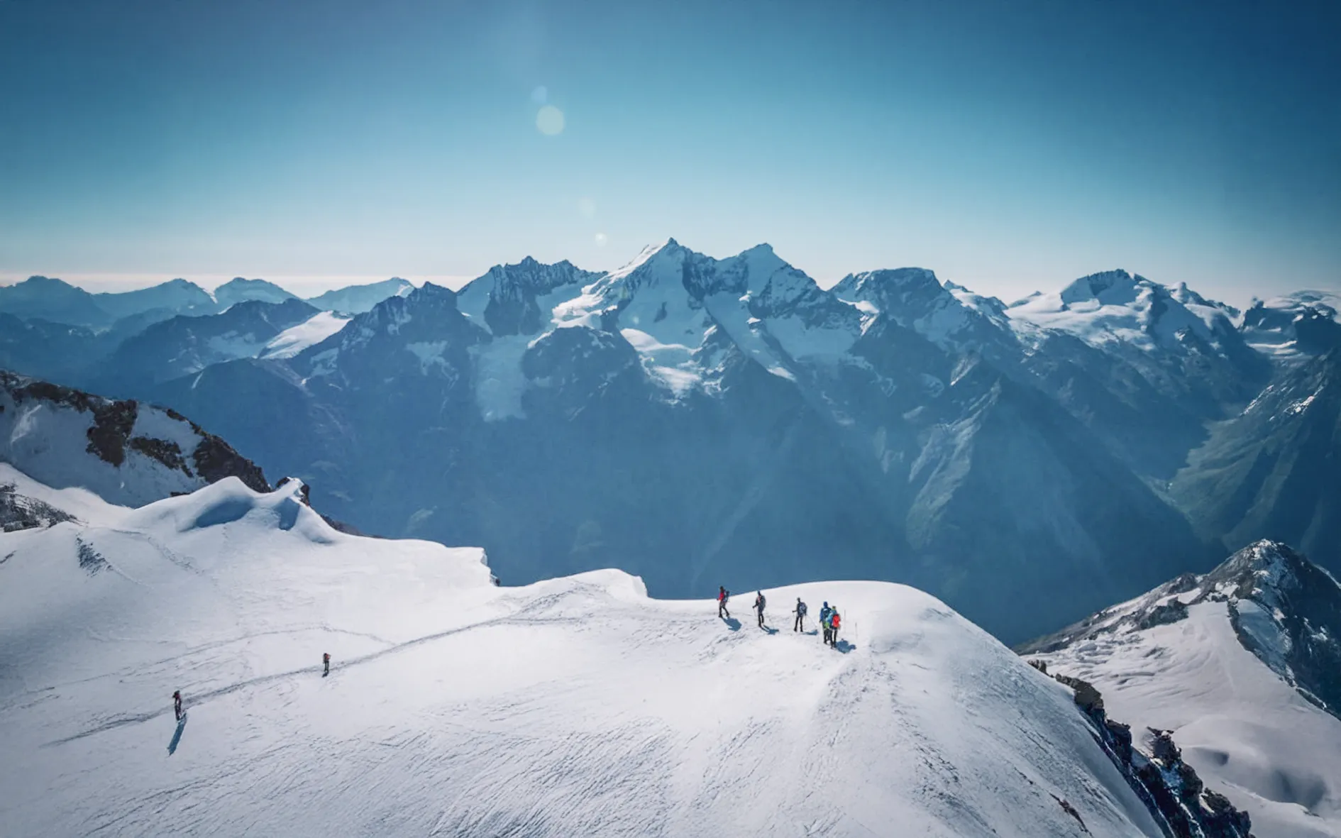 A breathtaking Alpine panorama, with majestic snow-capped mountains under a brilliant blue sky.