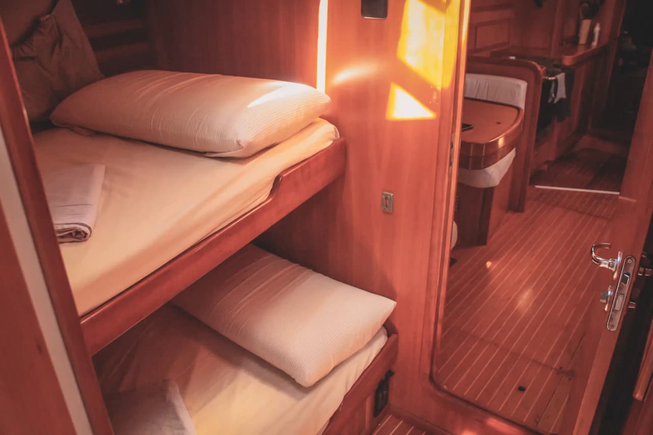 Cabine chaleureuse d'un voilier, avec lits confortables et bois poli, parfaite pour des escapades en mer.