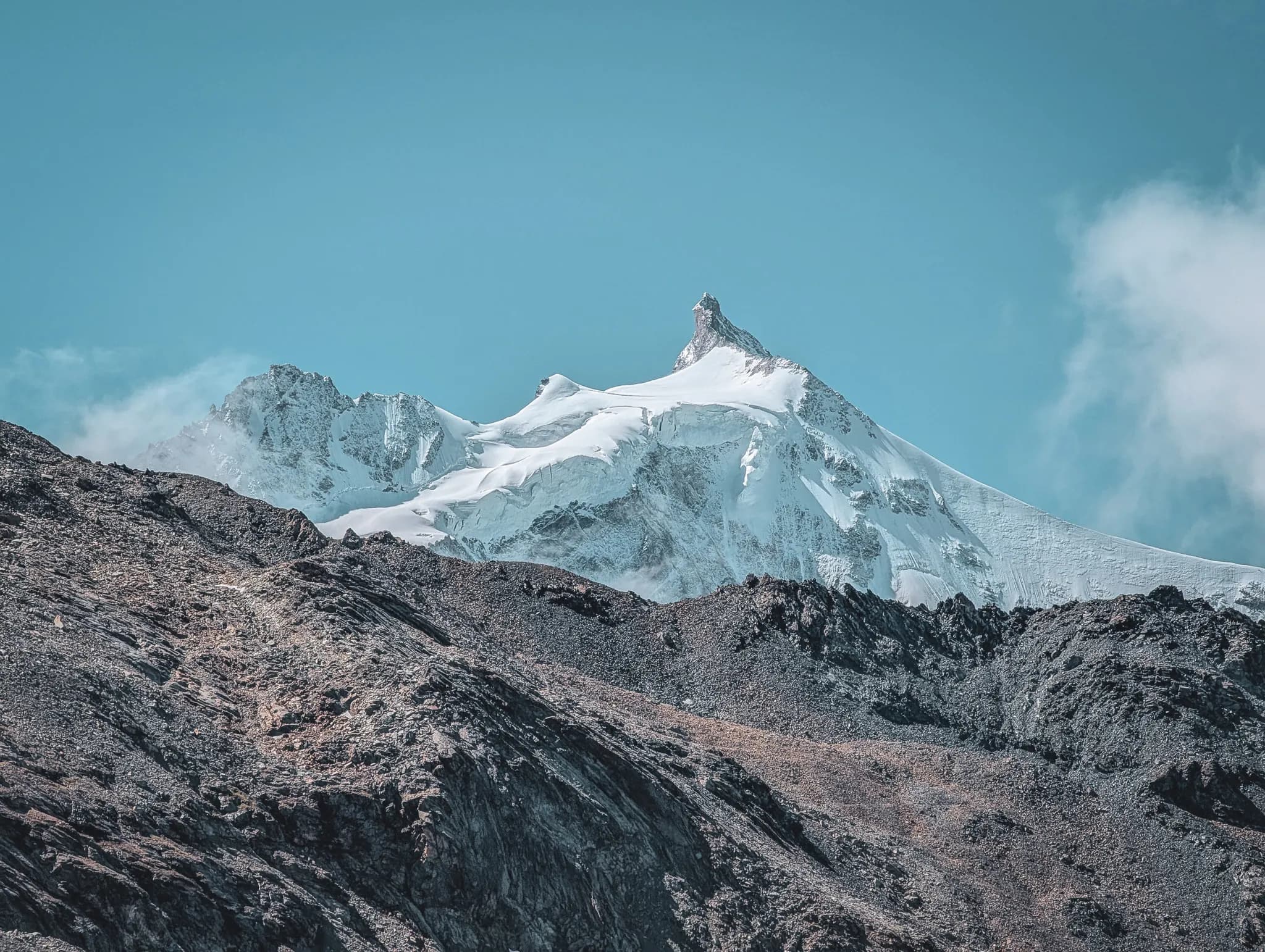 A majestic Alpine landscape unfolds, with snow-capped mountains illuminated by the golden hues of the setting sun. The peaks are covered in brilliant snow.