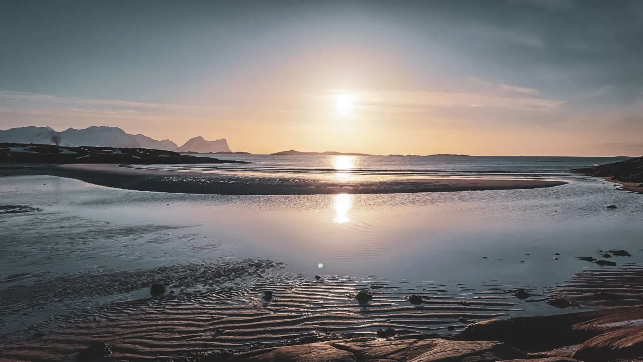 Sunset over the Senja fjords, magical reflections on the water, an enchanting landscape.