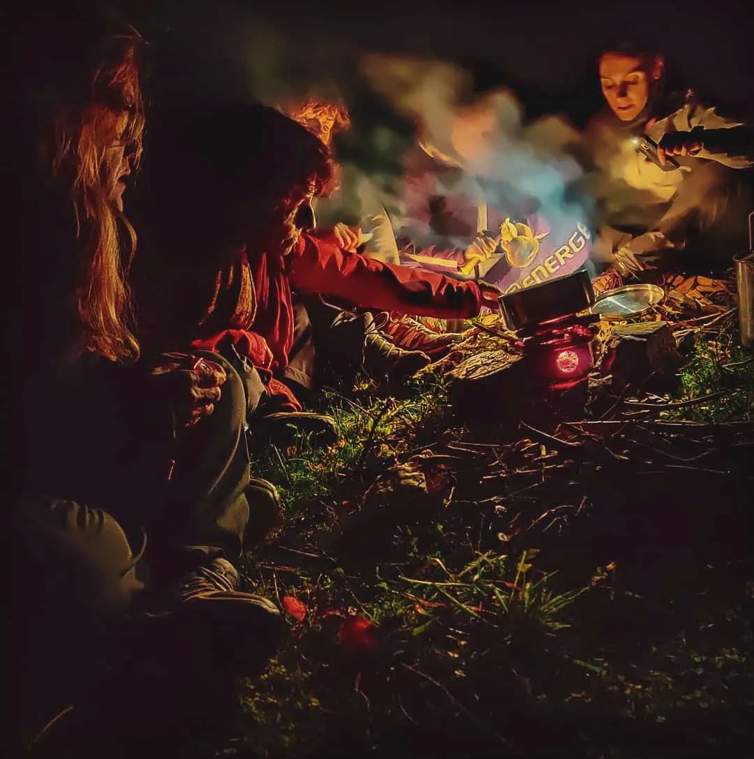 Groep rond een vuur, bushcraft leren op het platteland van de Vercors, warme sfeer.