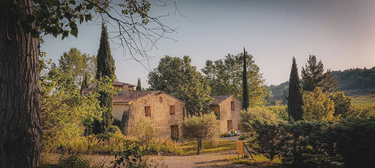 Charming stone house surrounded by greenery, under a clear sky, an invitation to escape.