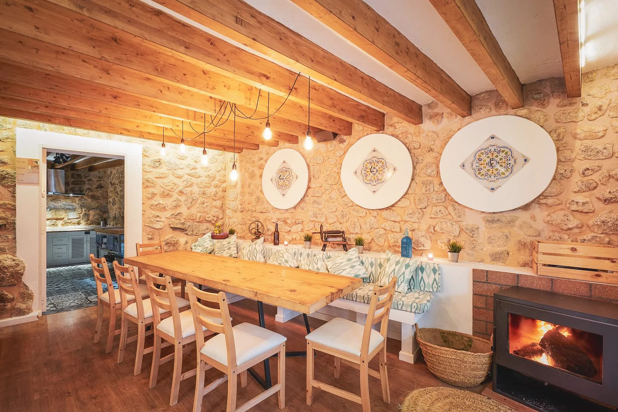 The warm interior of a Majorcan kitchen, with a large wooden table and stone walls.