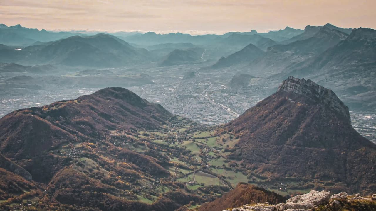 Vue panoramique des montagnes de Chartreuse, vallées verdoyantes et lumière douce du crépuscule.