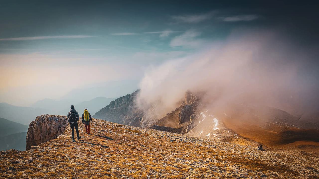 Hikers on a mountain path, surrounded by clouds, towards the peaks of the Vercors.