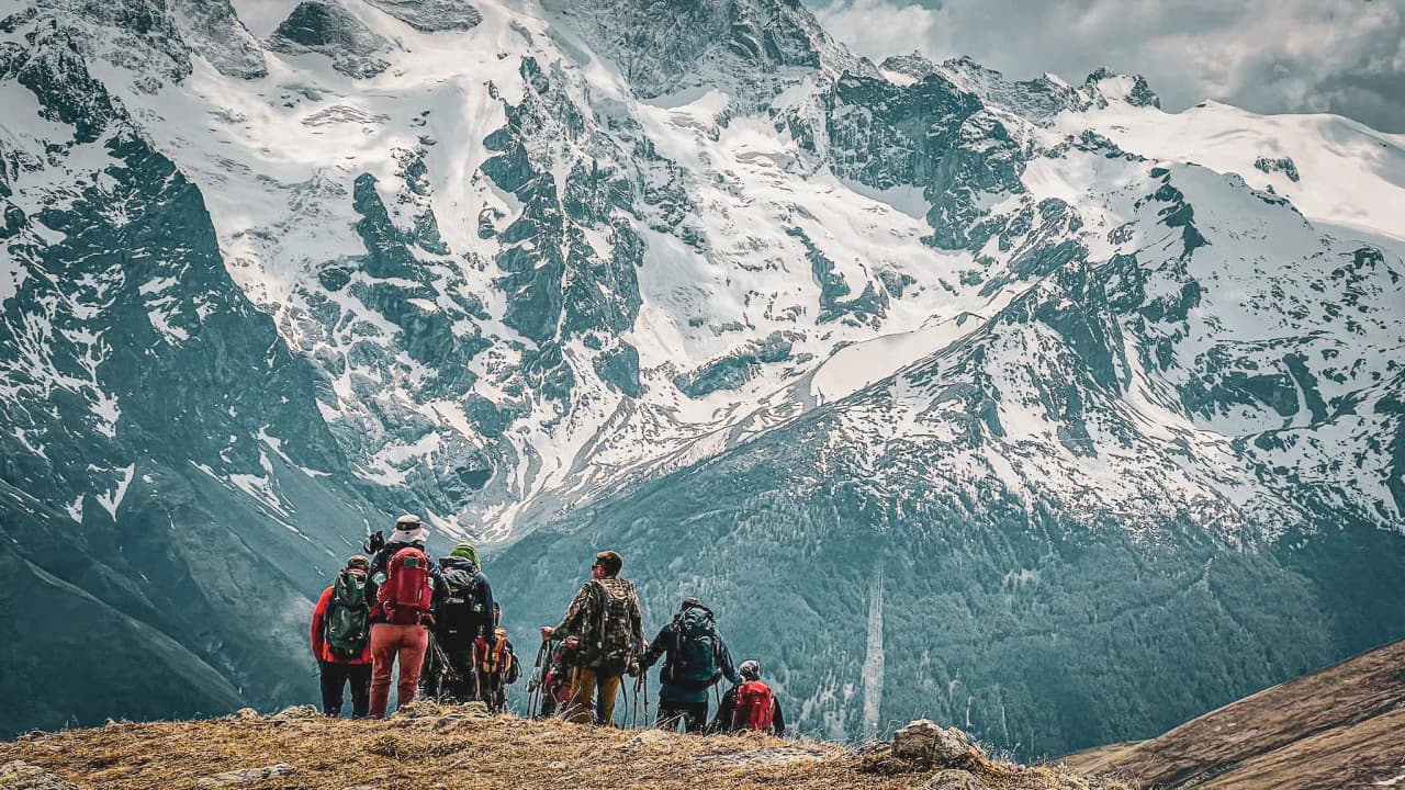 Un groupe de randonneurs admire des sommets majestueux, entouré de paysages alpins époustouflants.