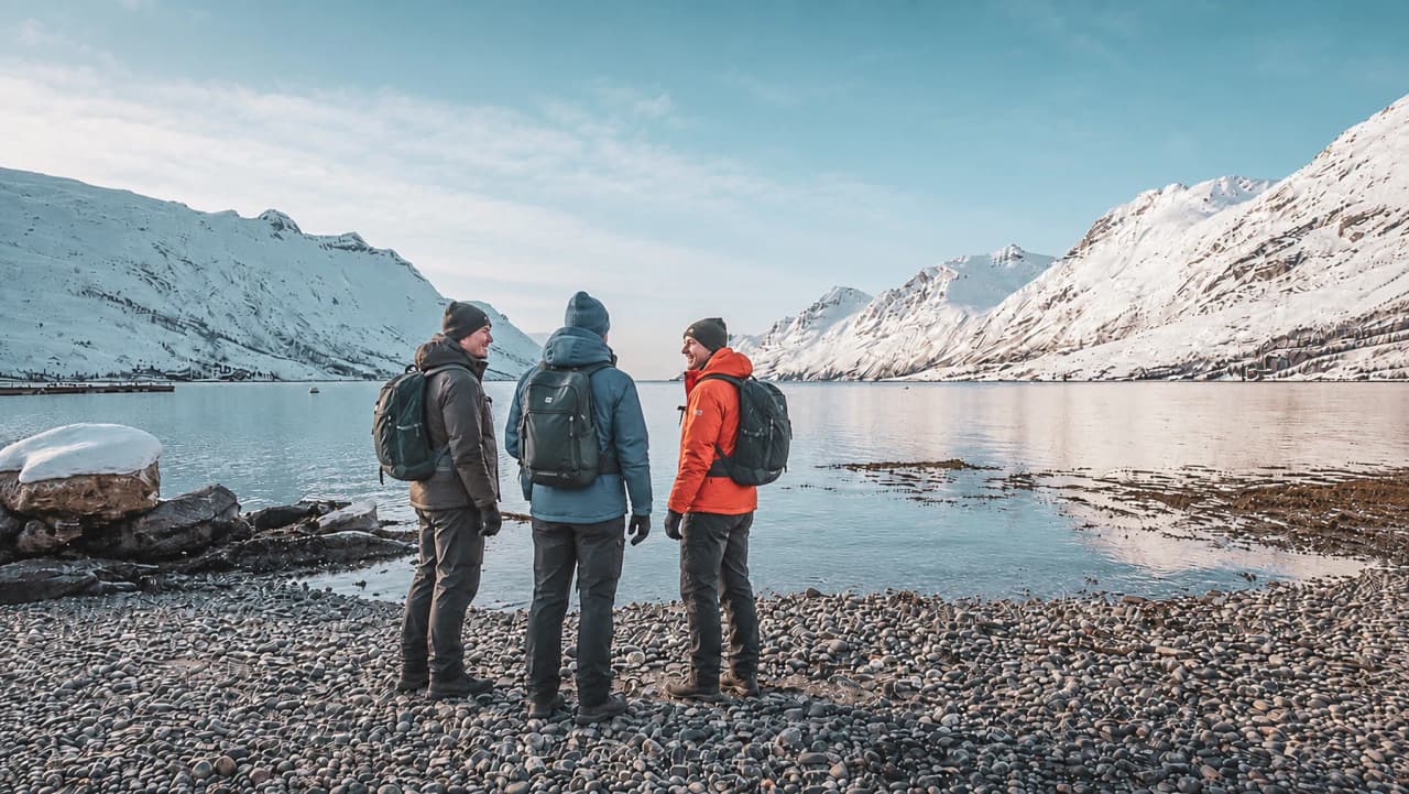 Drie reizigers bewonderen het besneeuwde landschap van de Noorse fjorden, klaar voor het avontuur.