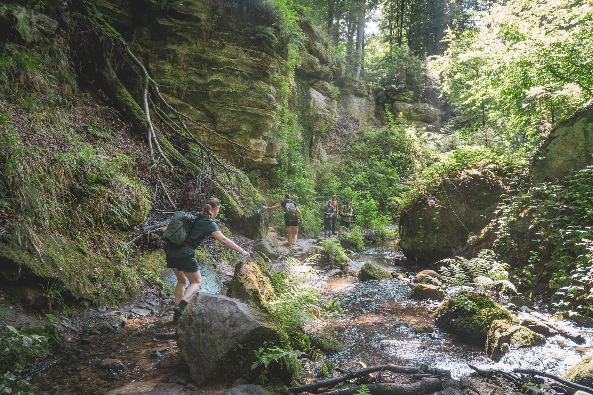 Een groep wandelaars verkent Luxemburgs Klein Zwitserland, tussen rotspartijen en groene bossen.