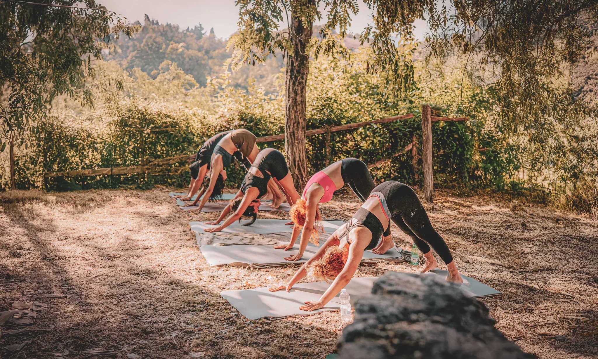 A group of people practising yoga outdoors in sunny Italy.