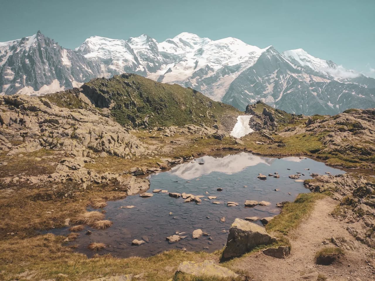 Paysage alpin enchanteur avec sommets majestueux, un étang reflétant la nature d'exception.