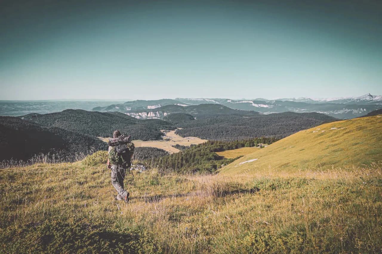 A hiker exploring the mountainous landscapes of the Vercors, between green meadows and summits.