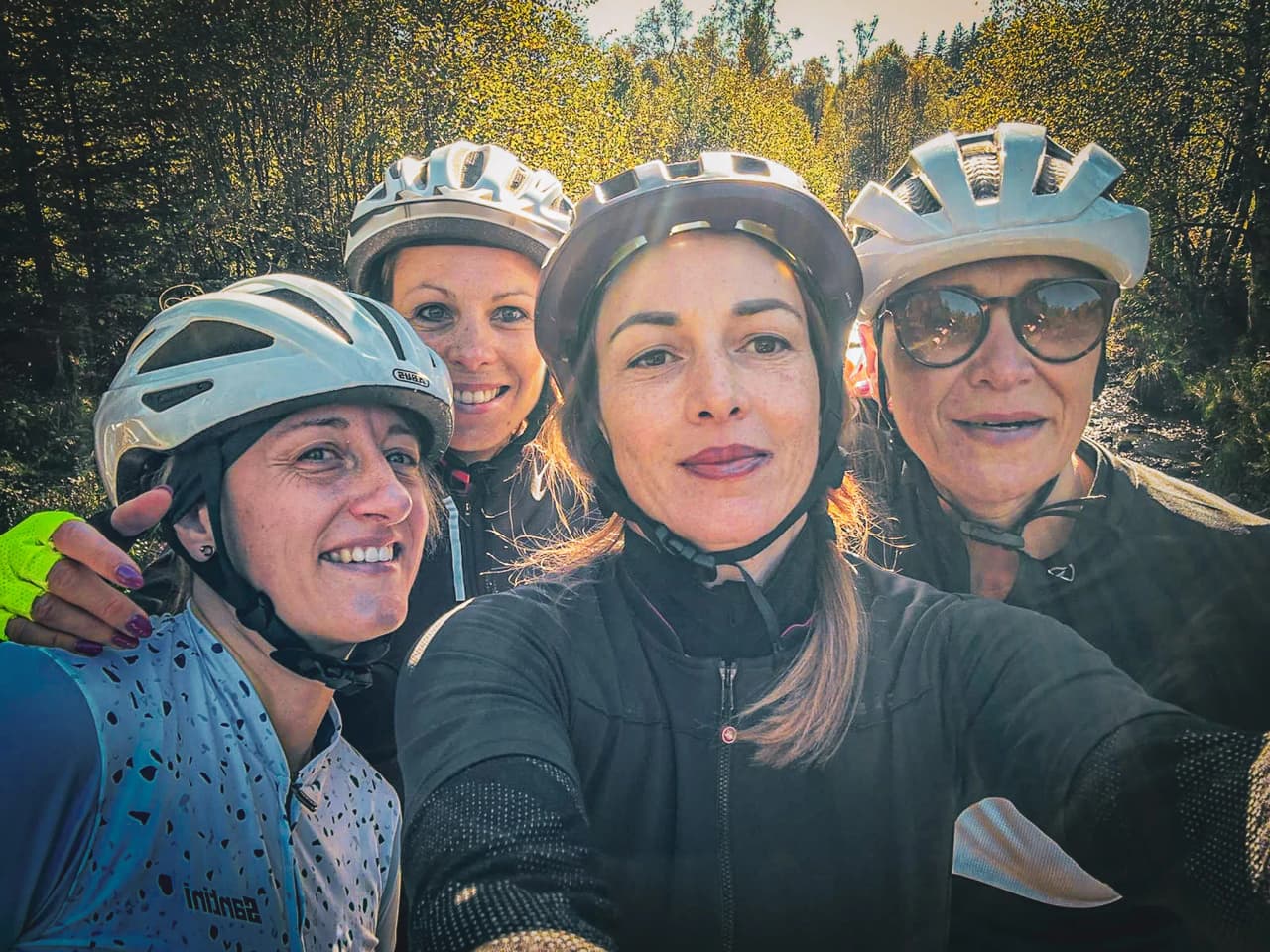 Vier lachende vrienden op de fiets, helmen op, omringd door de gouden natuur van de Hoge Venen.