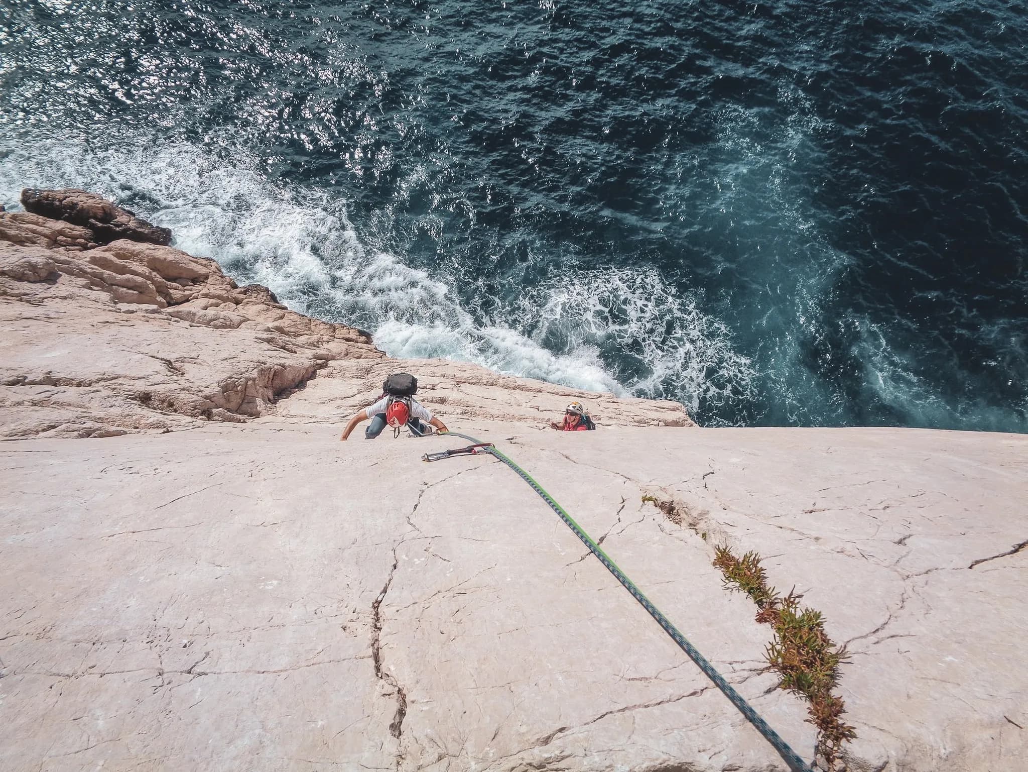 Escalade au bord des Calanques, mer bleu azur et falaises majestueuses en toile de fond.