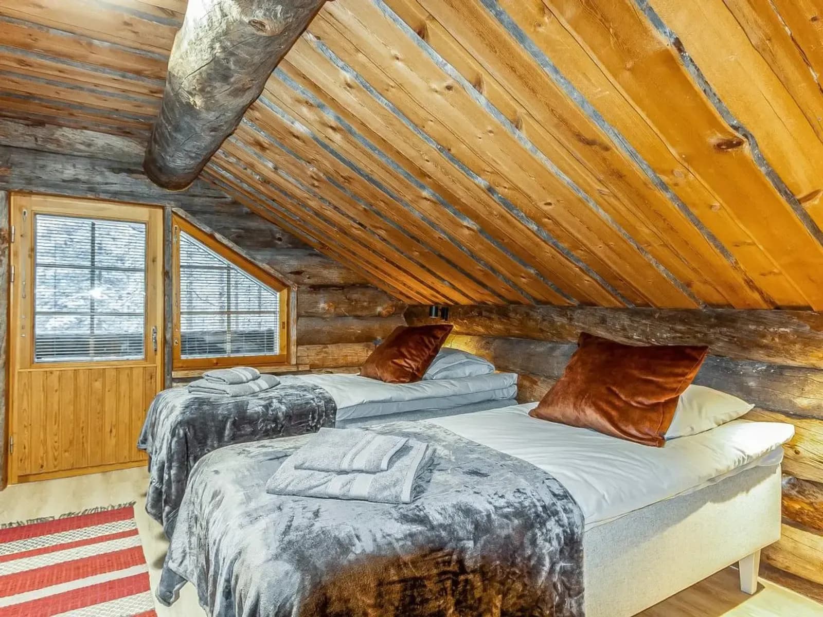 Chambre cosy en bois avec lits confortables et vue sur la neige, idéale pour un séjour en Laponie.