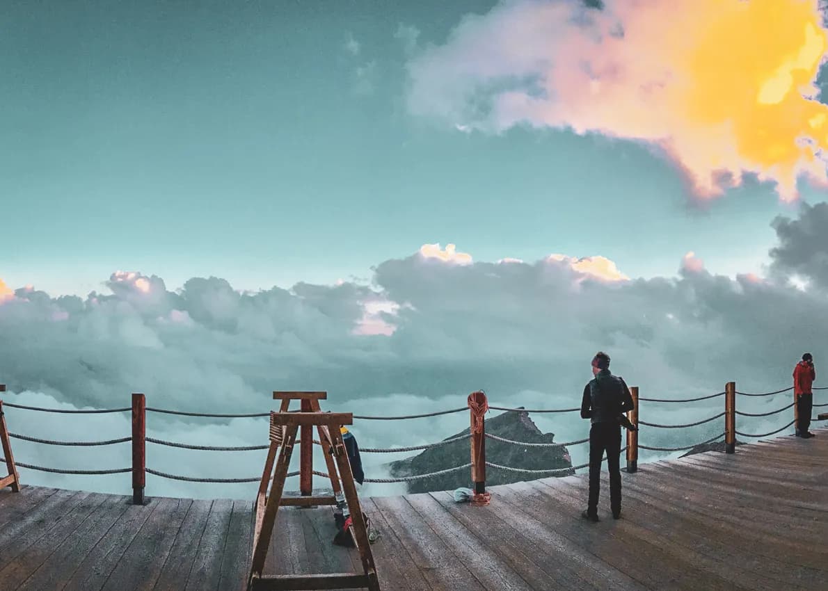 Two hikers contemplate a spectacular panorama of clouds and mountains at Mont Rose.