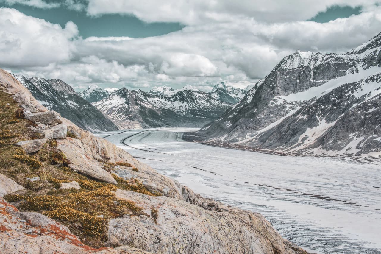 Panoramic view of the Aletsch glacier, surrounded by majestic mountains and floating clouds.