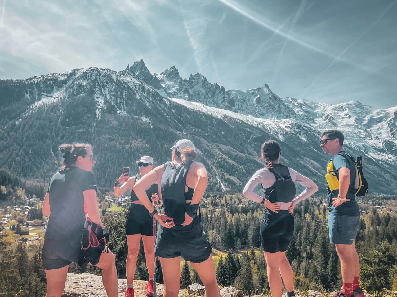 Een groep trailrunners bewondert het Mont-Blanc massief onder een zonnige hemel.
