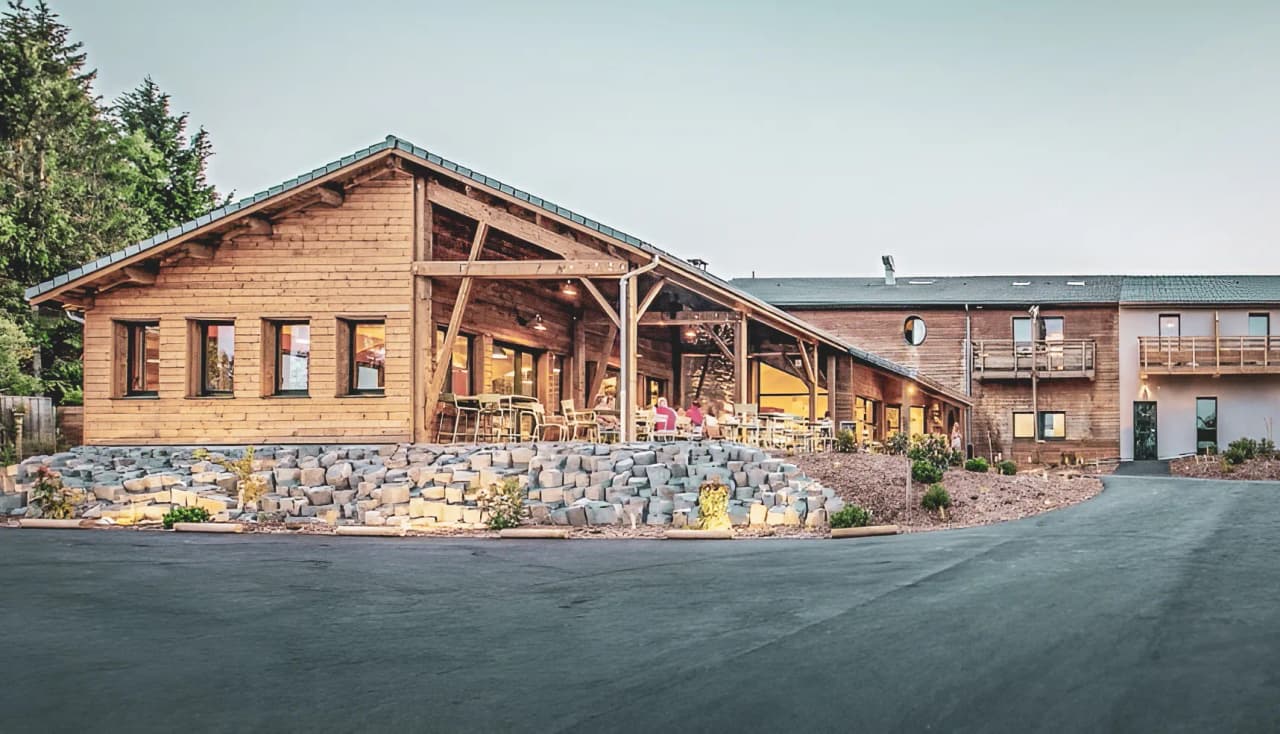 Une charmante auberge en bois, entourée de verdure, idéale pour un séjour en pleine nature en Auvergne.