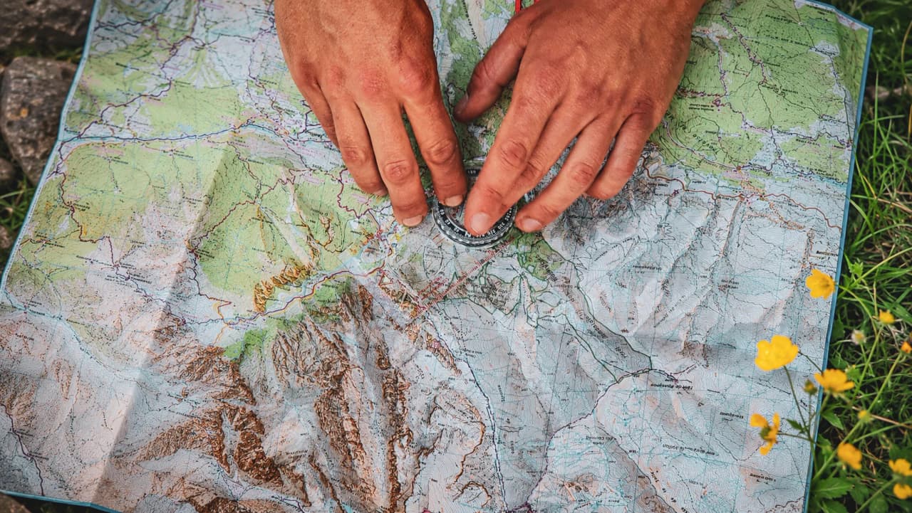 Deux mains posées sur une carte détaillée, préparant une aventure dans la vallée de l'Ubaye.