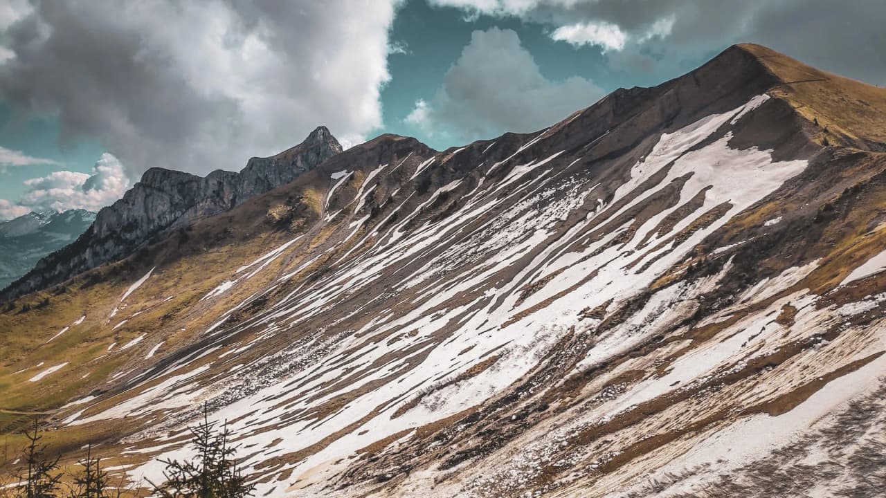 Mountain scenery in the Hautes Bauges with ridges, remaining snow and dramatic clouds.