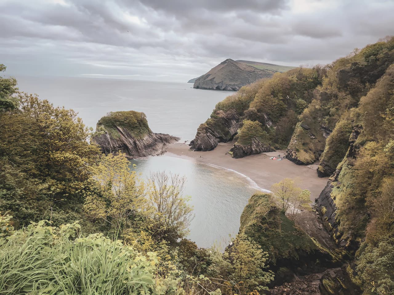 Côte sauvage galloise avec plages cachées, falaises verdoyantes et ciel nuageux. Un paradis à explorer.