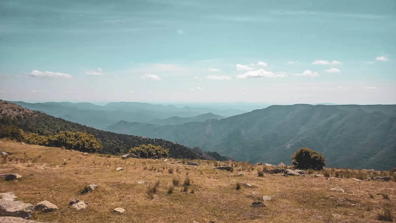 Landschappen van de Cevennen, groene heuvels, blauwe lucht en verspreide wolken, een uitnodiging om te reizen.
