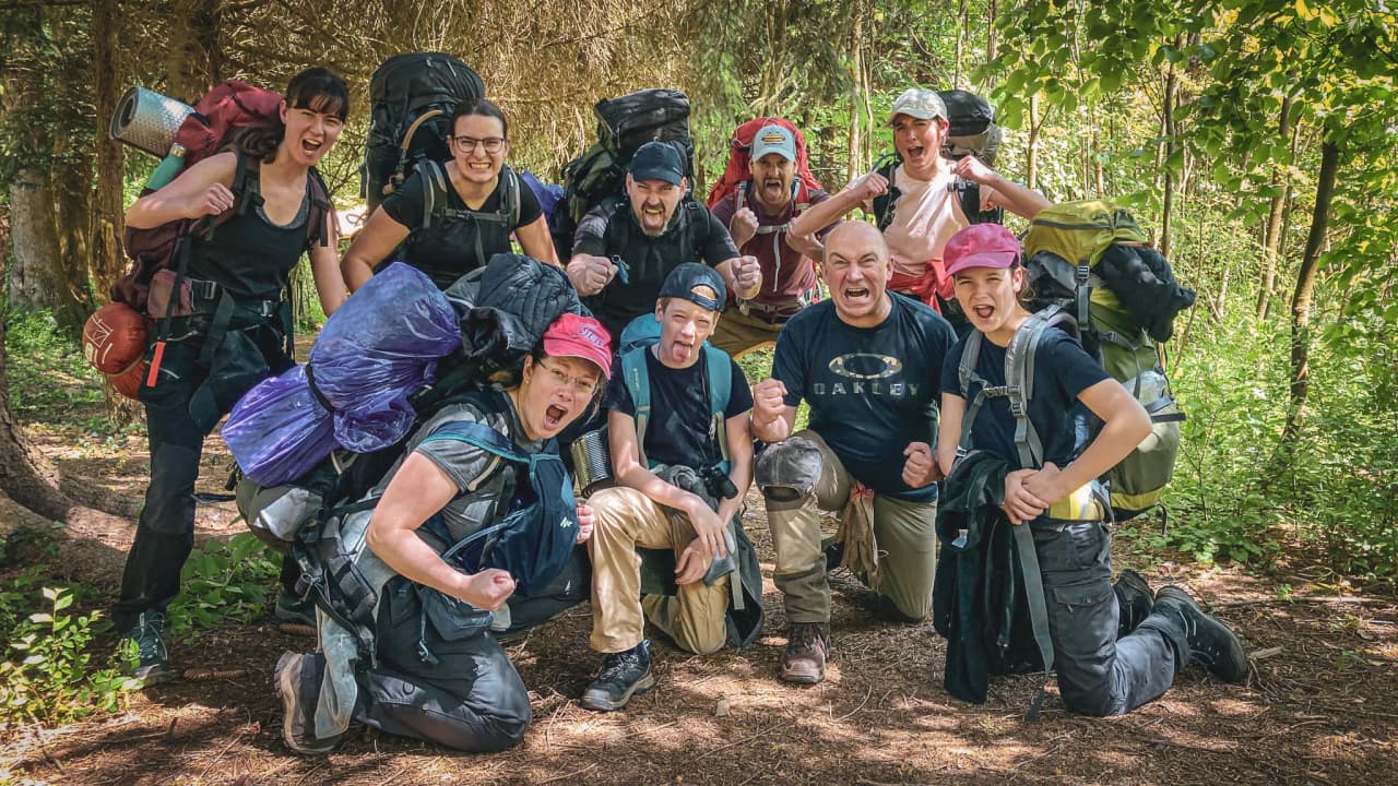Groupe enthousiaste en pleine forêt, prêts pour une aventure de survie en pleine nature.