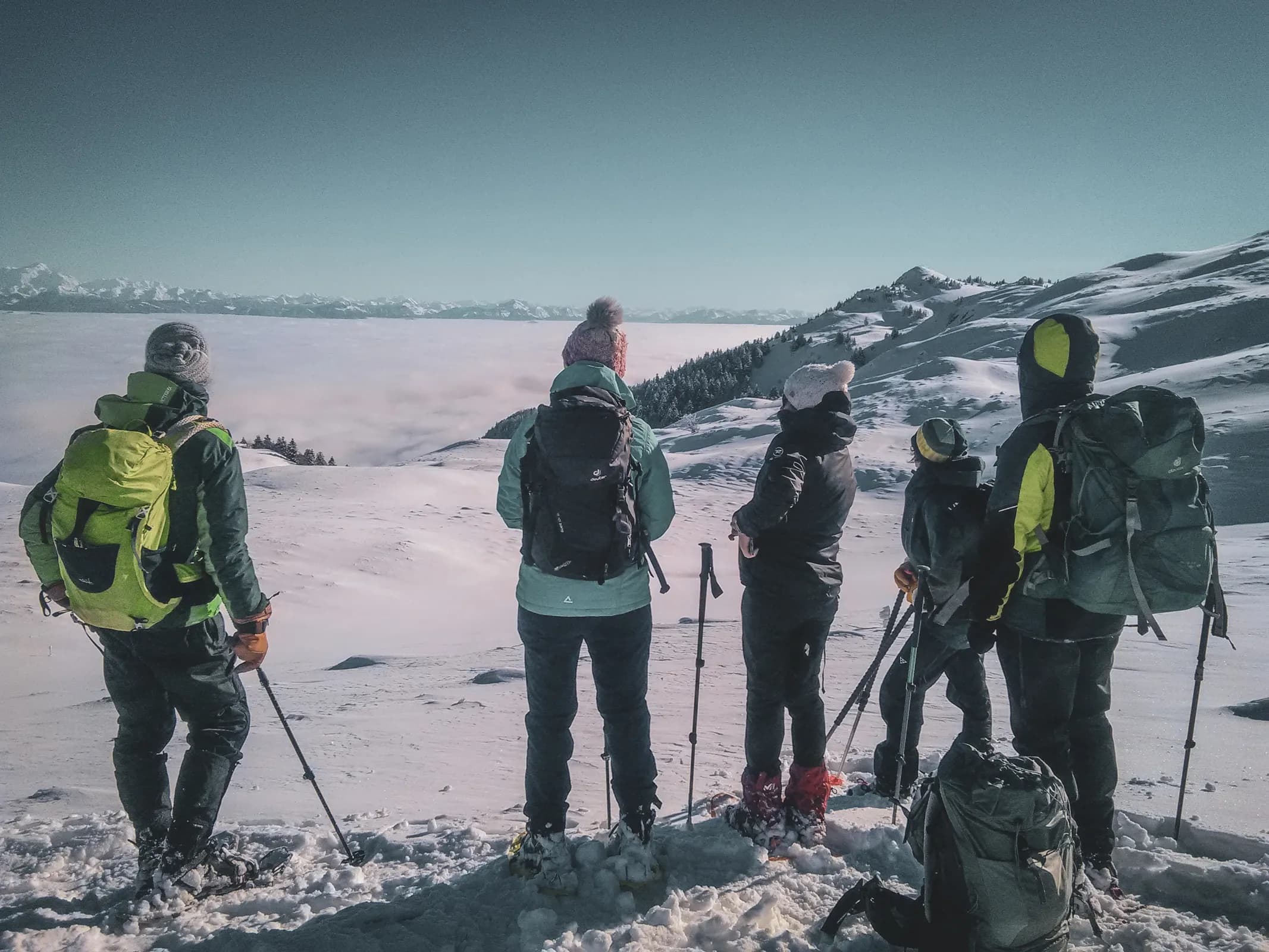 Cinq randonneurs admirent un panorama neigeux, prêts pour une aventure hivernale dans le Jura.